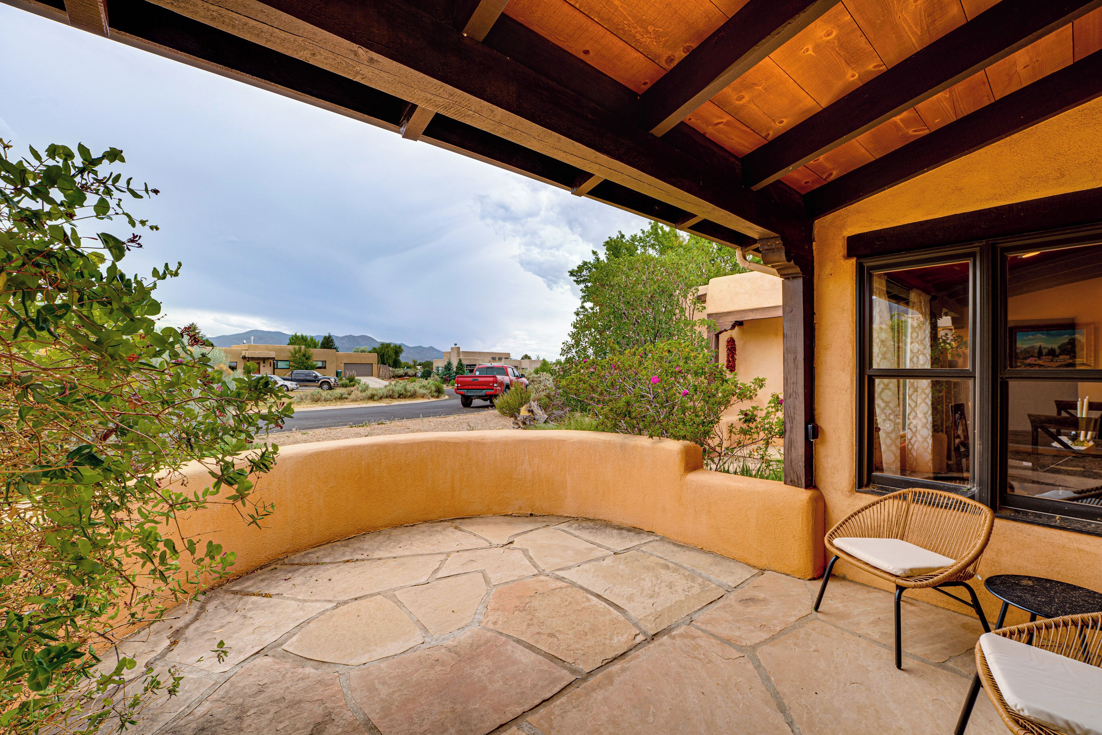 A patio with stone flooring, wicker chairs, and a view of the street and mountains.