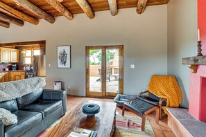 A living room with a sofa, armchair, coffee table, and a fireplace. - Adobe-style Home With Great Views! (Taos)