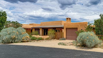 A single-story adobe-style house with a front porch, a garage, and a driveway.