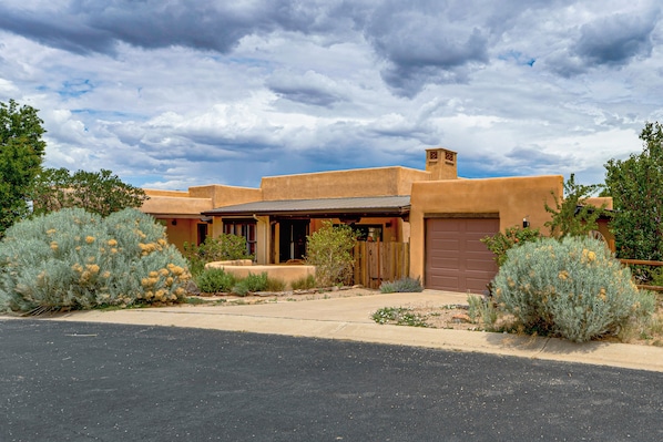 A single-story adobe-style house with a front porch, a garage, and a driveway. - Adobe-style Home With Great Views! (Taos)