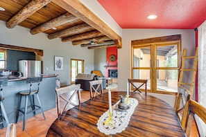 A spacious kitchen with wooden beams, a refrigerator, and a dining area with a table set for four. - Adobe-style Home With Great Views! (Taos)
