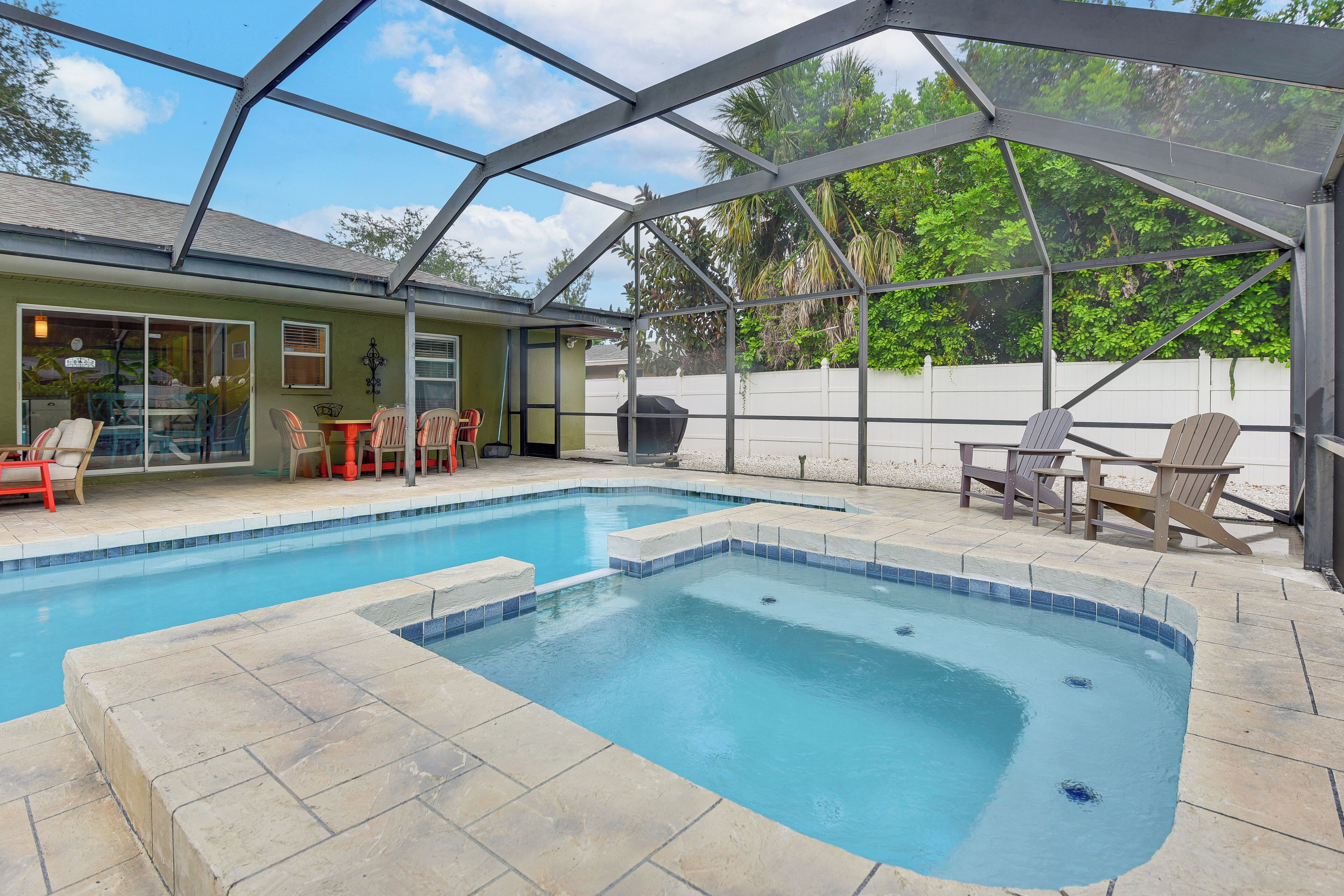 A swimming pool with a glass enclosure, outdoor seating, and a covered patio area.