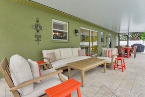 A covered patio area with a sofa, wooden table, chairs, and a barbecue grill. - 4 Mi to Siesta Key Beach! Spacious Family Getaway (Sarasota)