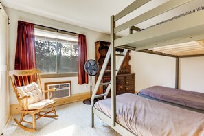 Ein Schlafzimmer mit Etagenbett, Schaukelstuhl, Ventilator und Kommode.
