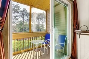A balcony with a glass door, a table, and two chairs. - Walk to Weirs Beach! Family Escape w/ Balcony (Laconia)