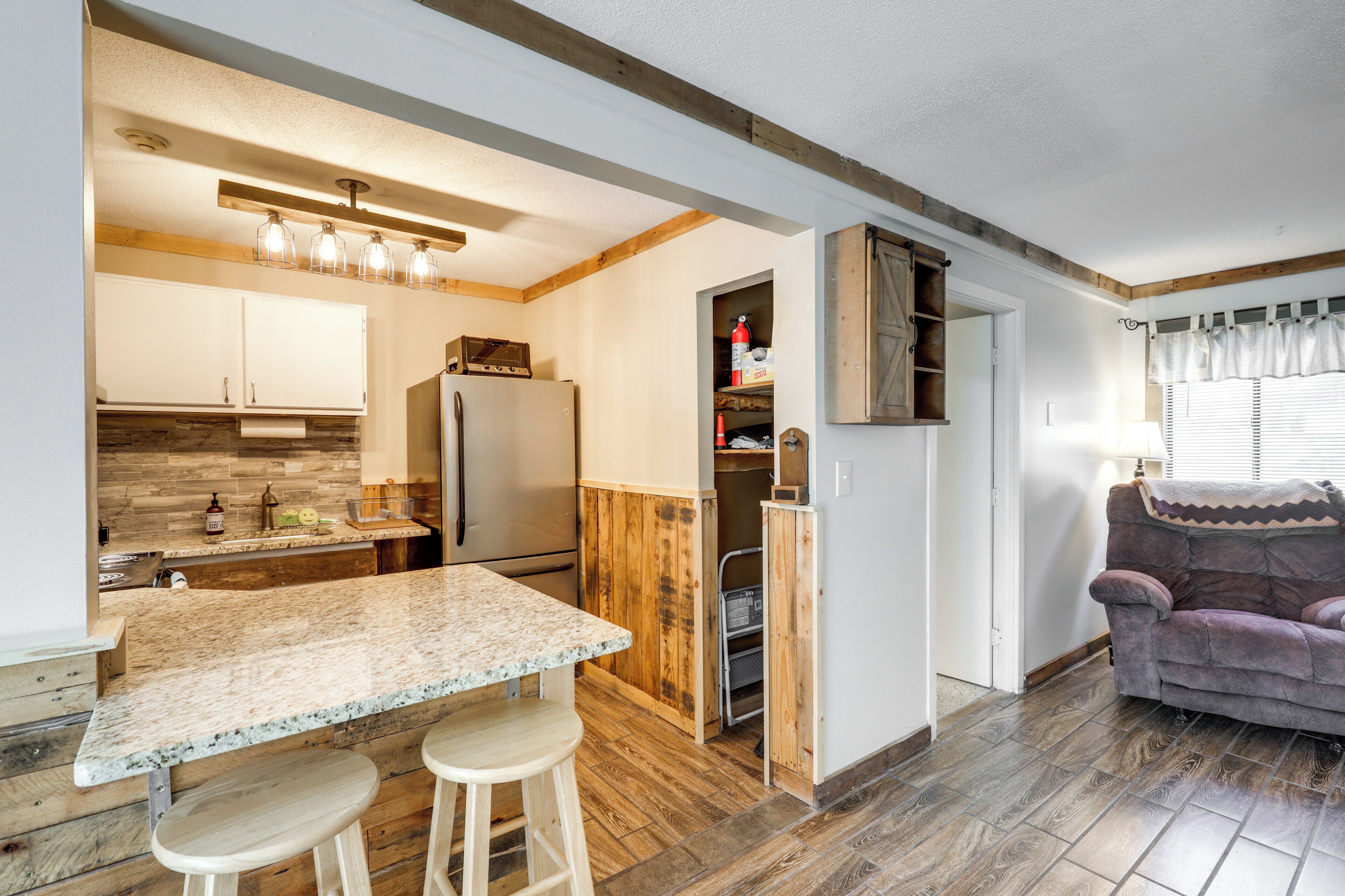 A kitchen with a marble countertop, wooden flooring, and a built-in refrigerator.