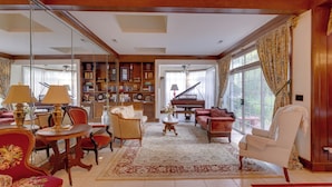 A spacious living room with a grand piano, a large bookshelf, and a red armchair.