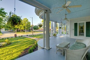 A porch with white wicker furniture, a hanging plant, and a ceiling fan.