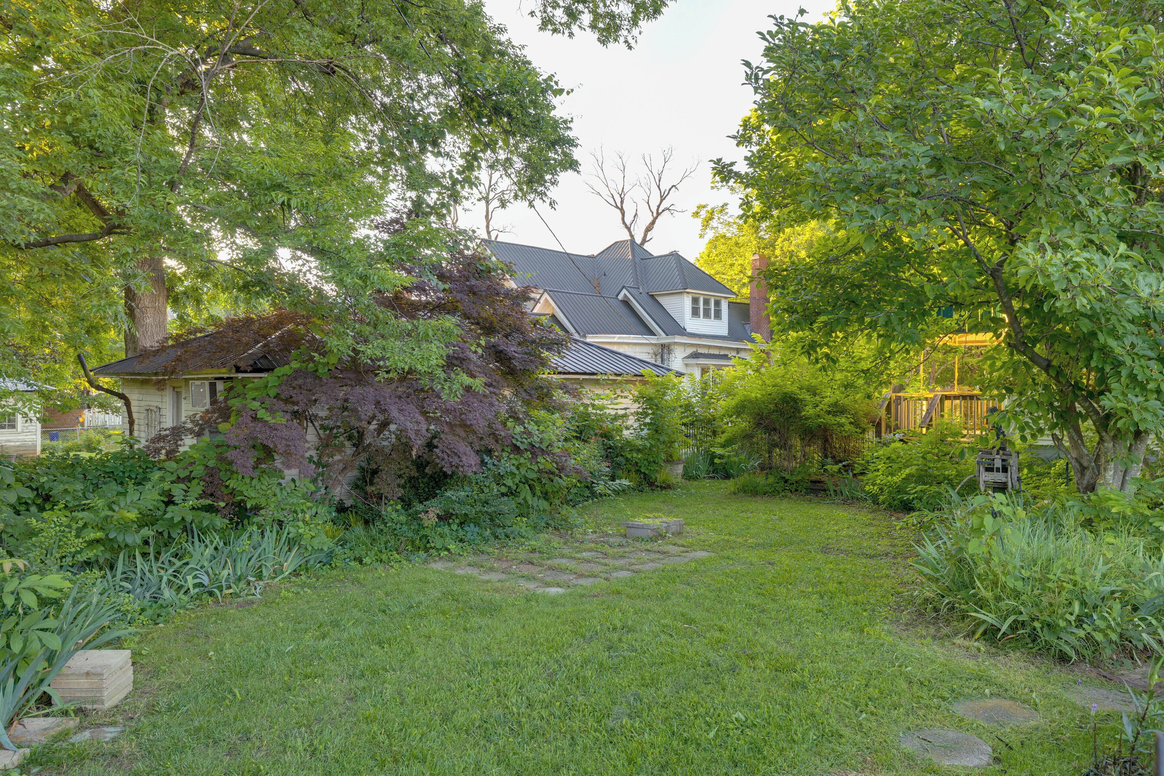 A residential property with a well-maintained lawn, a stone pathway, and a house with a dark roof and white walls.
