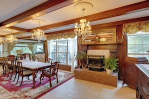 Un comedor con una gran mesa, sillas, candelabros y chimenea.