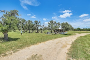 A rural landscape with a dirt path, trees, and a small building. - Romantic Wine Country Cabin Near Fredericksburg (Harper)