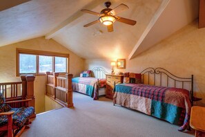 A bedroom with two beds, a ceiling fan, a window, and a dresser.