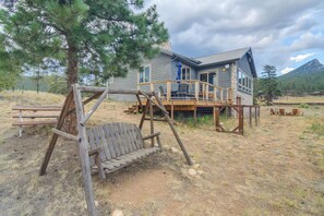 Ein rustikaler Holzhockel und ein Haus mit Steinuntergrund und einer Holzterrasse.