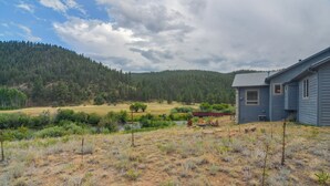 A house with a view of a forested hillside, a small stream, and a dry grassy field. - Colorado Riverfront Escape! Fish, Hike & Relax (Pine)