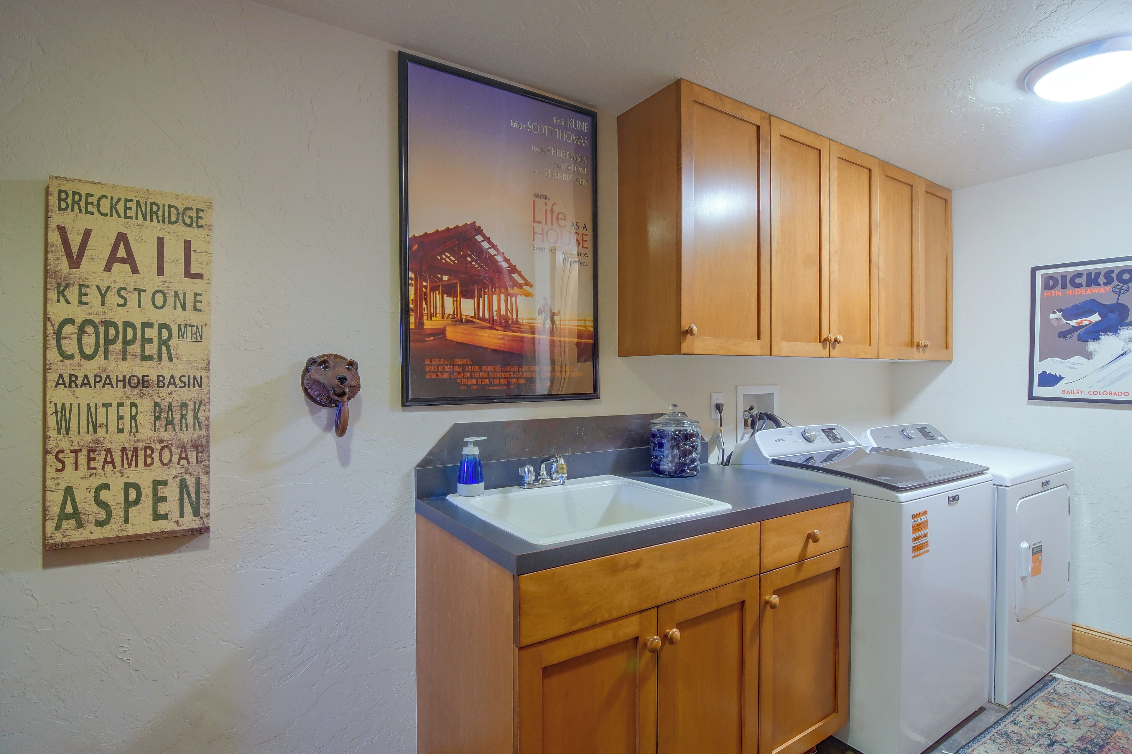 A kitchen with wooden cabinets, a sink, and a poster on the wall.