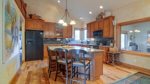 A kitchen with wooden cabinets, a refrigerator, a microwave, and a dining area with chairs. - Colorado Riverfront Escape! Fish, Hike & Relax (Pine)