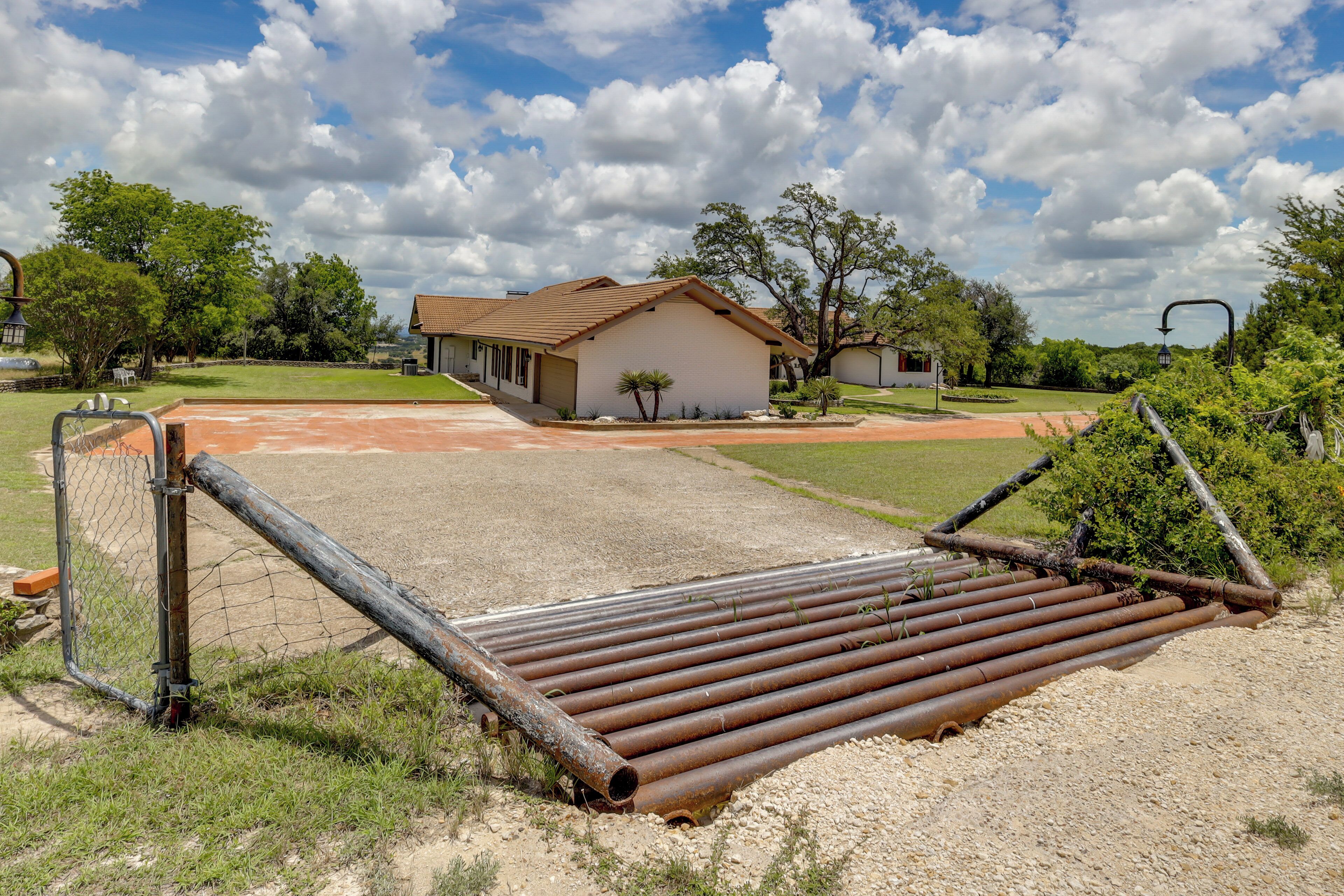 A fenced area with a dirt path leading to a building with a red roof.