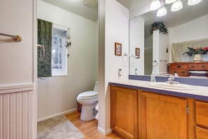 A bathroom with a wooden vanity, a sink, a toilet, and a window with a curtain. - 1 Mi to Beach! Lush Florence Retreat w/ Sunroom (Florence)