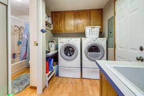 A laundry room with two front-loading washing machines, a drying rack, and wooden cabinets. - 1 Mi to Beach! Lush Florence Retreat w/ Sunroom (Florence)