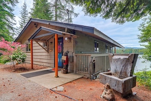 A cabin with a porch, a wooden deck, a dock, and a lake view. - Private Dock, Deck & Yard: Luxe Sacheen Lake Home (Newport)
