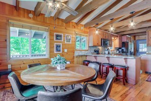 Ein Holzinterieur mit einem runden Esstisch, Barhocker und einer Küchenzeile.