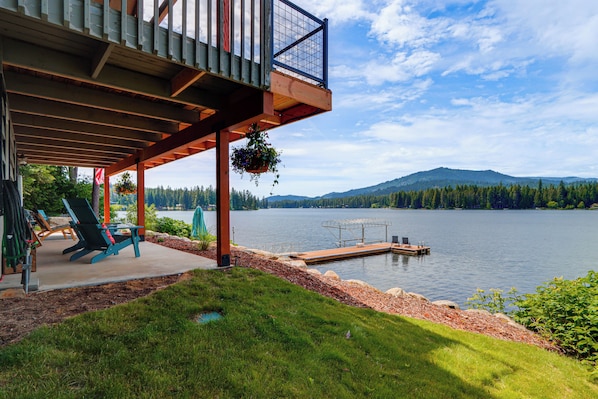 A lakeside deck with chairs, a dock, and a hanging planter. - Private Dock, Deck & Yard: Luxe Sacheen Lake Home (Newport)