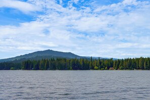 A calm lake with a forested hill in the background. - Private Dock, Deck & Yard: Luxe Sacheen Lake Home (Newport)