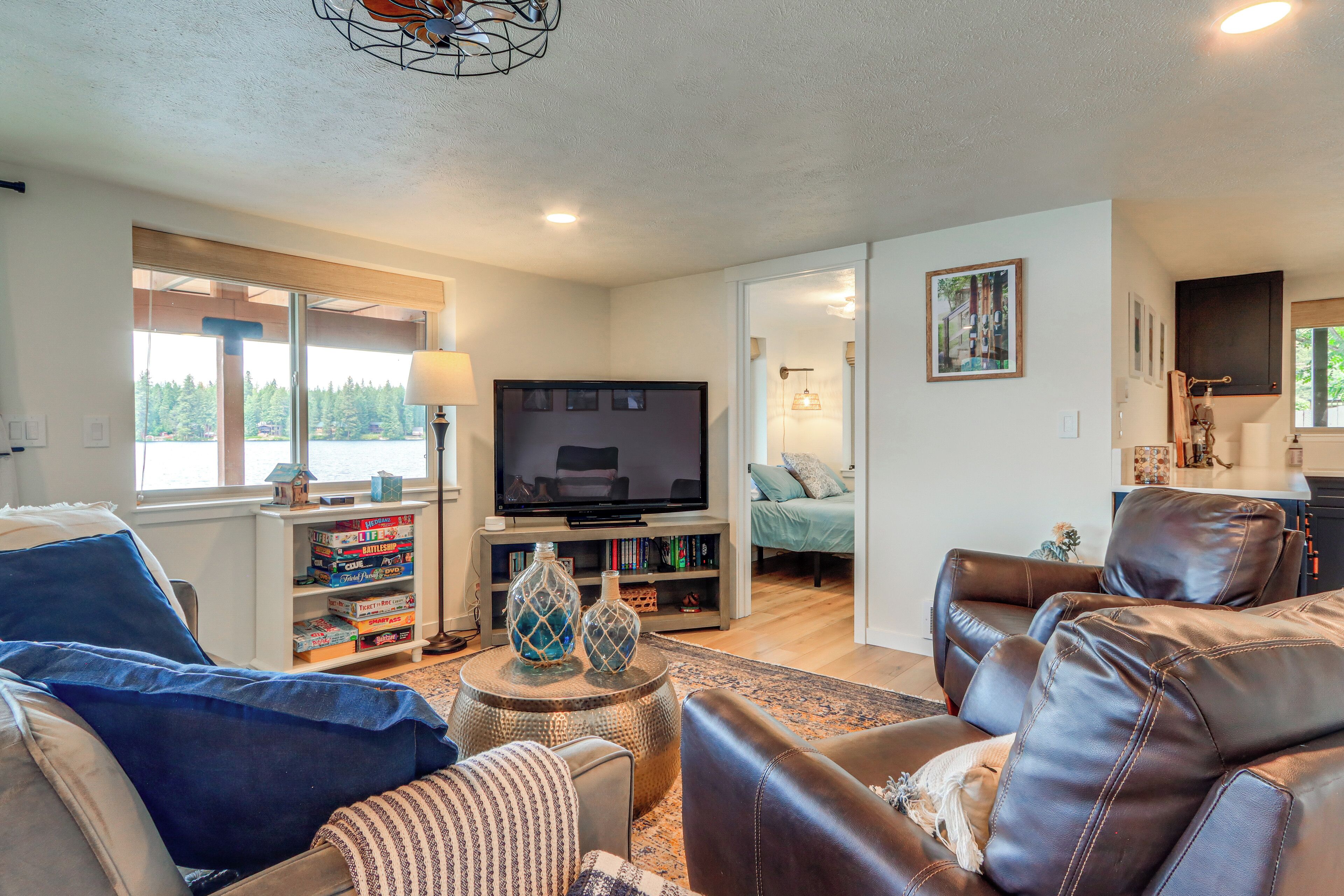 A living room with a television, leather sofas, a bookshelf, and a view of the outdoors.