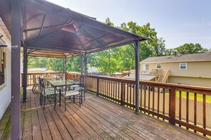A covered outdoor deck with a table and chairs, a wooden railing, and a view of a residential area. - 10 Mi to Beach! Group-friendly Bayville Getaway (Bayville)