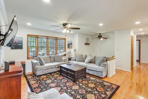 A living room with a sectional sofa, a coffee table, a patterned rug, and ceiling fans. - 10 Mi to Beach! Group-friendly Bayville Getaway (Bayville)