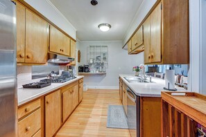 A kitchen with wooden cabinets, a stainless steel refrigerator, and a countertop with various appliances. - Iconic Finger Lakes Home Near Taughannock Falls (Trumansburg)