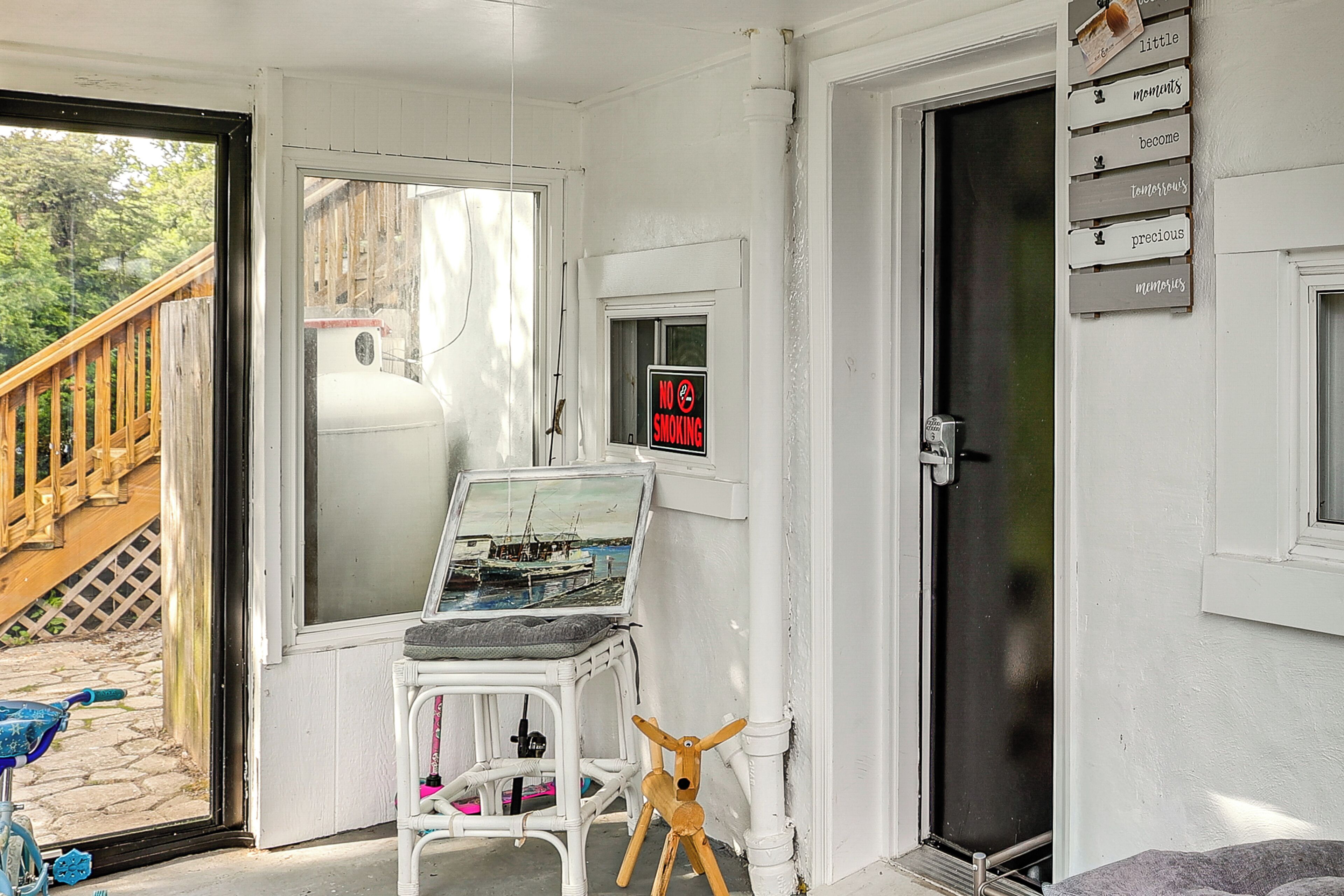 Una habitación con terraza de madera, una silla blanca, un juguete de madera, un letrero de 'No Fumar' y una pared con un cartel que dice 'los momentos se vuelven preciosos'.