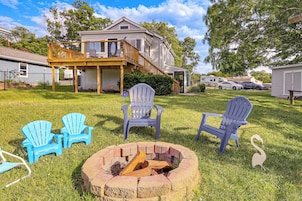 Una casa con terraza, un brasero y sillones Adirondack azules.