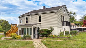 A two-story house with a covered porch, a small garden, and a wooden staircase leading to the upper level.