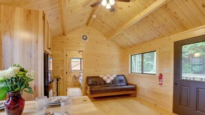 L’intérieur d’un chalet en bois comprend un coin repas, un canapé et une porte donnant sur l’extérieur.