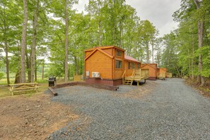 A cabin-style lodging area with multiple wooden cabins, gravel paths, and a picnic table. - Stunning Views! 3-cabin Retreat on 400-acre Farm (Middlebury Center)