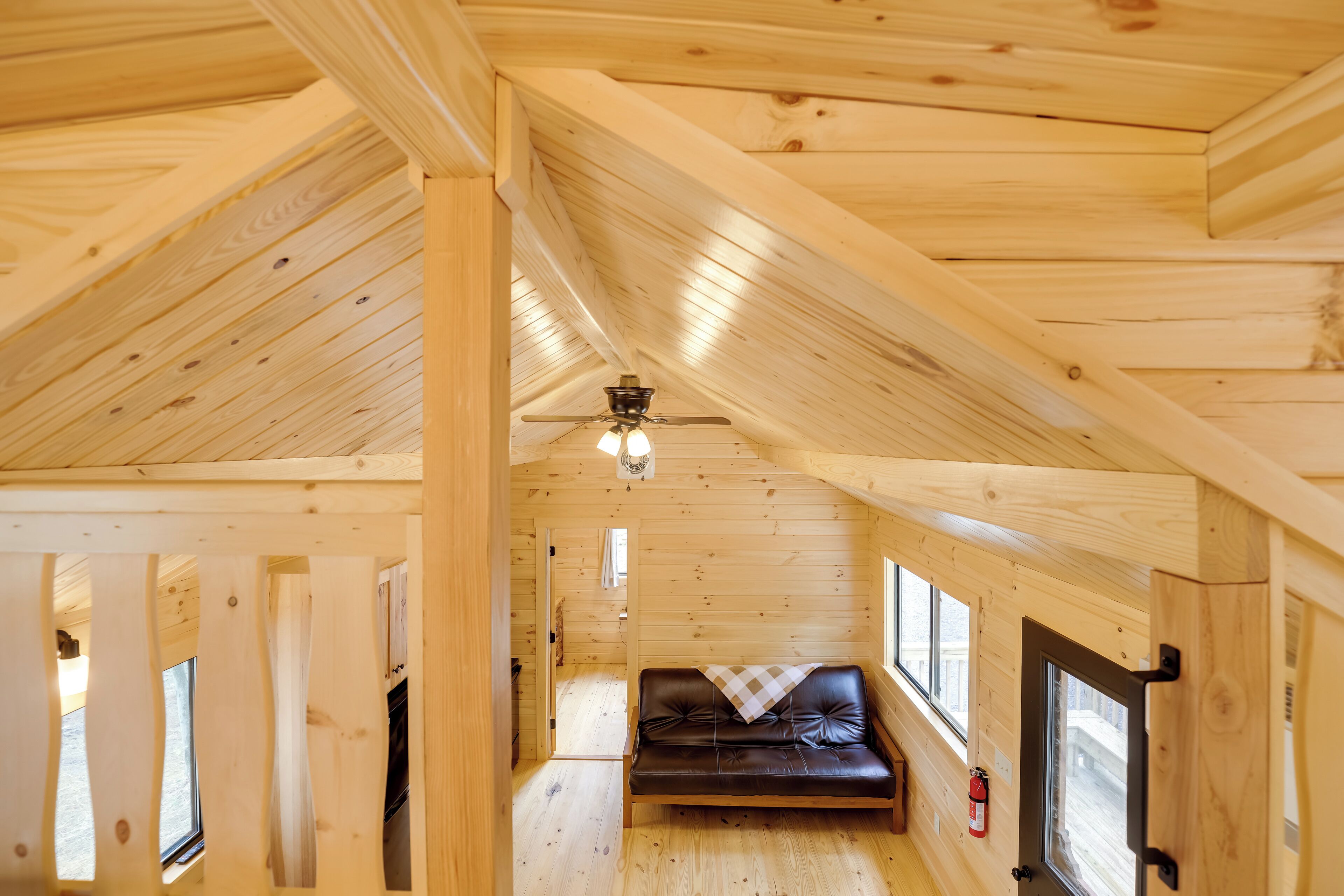Un interior de madera con un ventilador de techo, un sofá y ventanas.