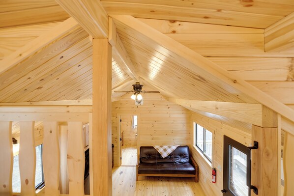 A cozy cabin interior with a wooden ceiling, a ceiling fan, a leather sofa, and a fire extinguisher. - Stunning Views! 3-cabin Retreat on 400-acre Farm (Middlebury Center)