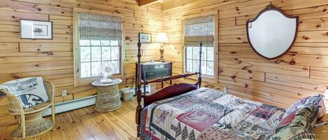 A wooden-paneled room with a bed, a chair, a lamp, and a mirror.