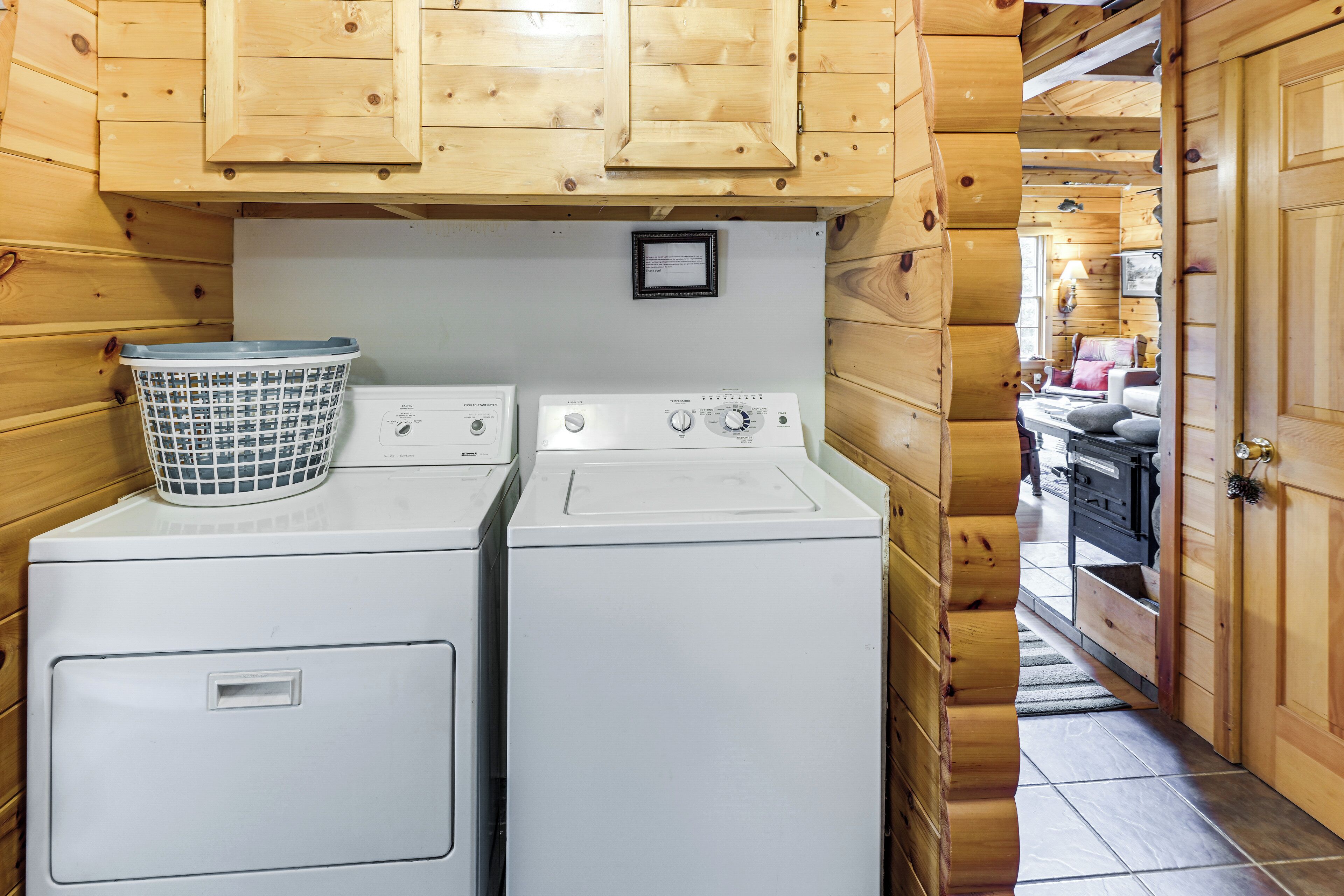 Une buanderie avec deux machines à laver blanches, un panier et des murs en bois.