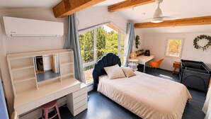 Een slaapkamer met een bed, bureau, stoel en een raam met gordijnen.