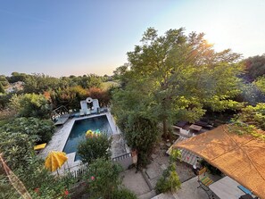 Ein Pool, umgeben von viel Grün, einer Pergola und einem überdachten Sitzbereich.