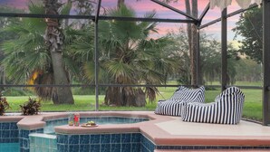 A pool area with a hot tub, striped cushions, and a view of palm trees. - Disney Villa: Pool, Spa & Mario Bros Game Room (Davenport)