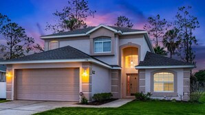 A two-story house with a garage, a covered entryway, and a well-maintained lawn. - Disney Villa: Pool, Spa & Mario Bros Game Room (Davenport)