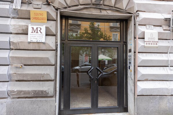 A building entrance with a glass door, signs indicating 'Centro Cardiologico' and 'Morpheus Rooms,' and a number '71' sign.