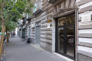 A building with a sign for 'IANNÒ Napoli Rooms' indicating a hotel. There are outdoor seating areas and a tree on the sidewalk. - Iannò Napoli Rooms (Naples)