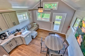 A kitchen with a dining area, wooden cabinets, a ceiling fan, and large windows.