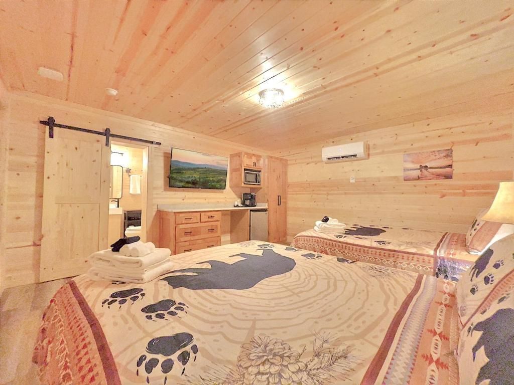 Une chambre de style cabane en bois, avec un lit, un bureau, un four à micro-ondes et une vue sur l’extérieur.