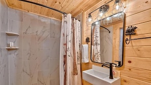 A bathroom with a shower, a sink, and a mirror. - Retreat on the Lake (Hiawassee)