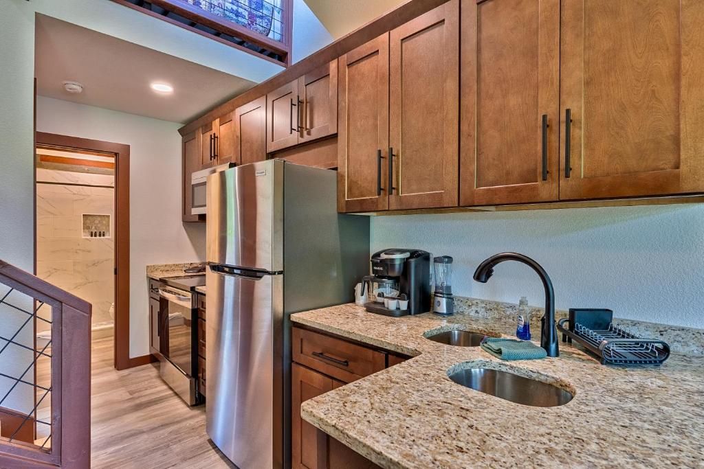A kitchen with wooden cabinets, stainless steel appliances, granite countertops, a double sink, and a coffee maker.
